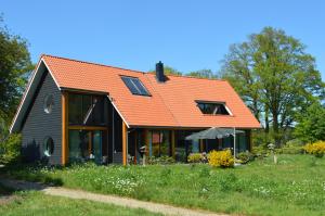 una casa con techo naranja en un campo verde en Erve Grootenhuys en Deurningen