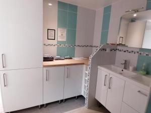 La salle de bains est pourvue de placards blancs et d'un lavabo. dans l'établissement L'Escale, chambres chez l'habitant, au Mans 19 autres photos
