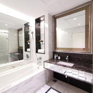 a bathroom with a tub and a sink and a mirror at Dorsett Residences Kuala Lumpur in Kuala Lumpur