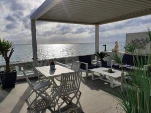 un patio con mesa, sillas y el océano en Beach-Front Bahia Dorada, en Estepona