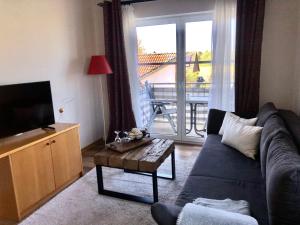 a living room with a couch and a tv and a table at Ferienwohnung Warnemünde - Landhaus Immenbarg in Diedrichshagen