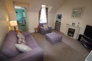 a living room with a purple couch and a fireplace at Easdale House Apartments in Inverness