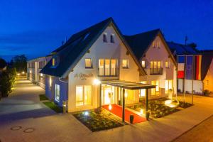 Un grand bâtiment blanc avec des lumières allumées la nuit dans l'établissement Hotel La Mirabelle, à Rheinhausen