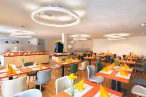 a restaurant with tables and chairs with yellow napkins at Hotel La Mirabelle in Rheinhausen