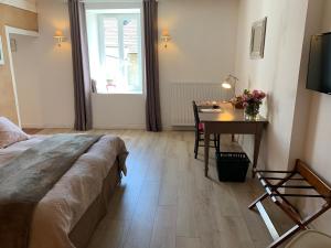 a bedroom with a bed and a desk and a window at La Colonie - Maison d'Hôtes in Collonges