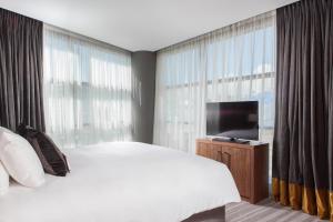 a bedroom with a large bed and a flat screen tv at Crowne Plaza Newcastle - Stephenson Quarter, an IHG Hotel in Newcastle upon Tyne