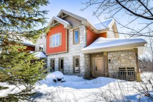 una casa con nieve en el suelo en House On The Golf La Bte -10min To Tremblant 150, en Mont-Tremblant