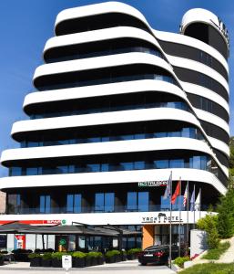 een zwart-wit gebouw met een auto voor de deur bij Yacht Hotel in Vlorë