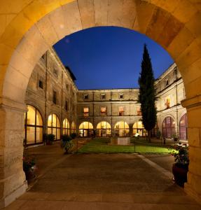 ein Torbogen in einem Gebäude mit einem Baum darin in der Unterkunft Hotel Real Colegiata San Isidoro in León