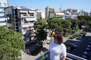a woman standing on a balcony looking at a city at Hotel Belvedere in Sottomarina
