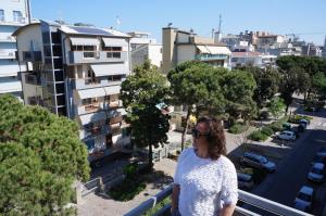 een vrouw op een balkon met uitzicht op een stad bij Hotel Belvedere in Sottomarina