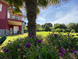 a palm tree and flowers in front of a house at Apartamentos La Ardina Celorio in Celorio