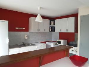 a kitchen with red and white cabinets and a counter at Gite de la Croix du Hêtre in Hambers