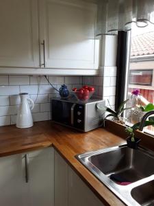 a kitchen counter with a microwave and a sink at Naturnära enkel rum B&B i Uppsala Ramstalund in Uppsala