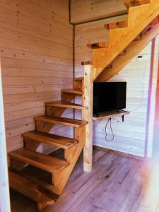 Habitación con escaleras y TV en una cabaña de madera. en Domki u Danki, en Brenna