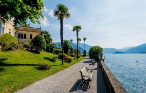 uma fila de bancos de parque ao lado de uma massa de água em Grand Hotel Villa Serbelloni - A Legendary Hotel em Bellagio