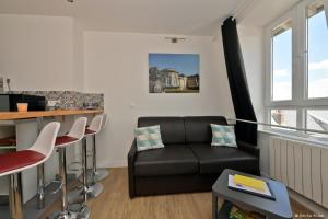 a living room with a black couch and a bar at Comme à la Maison - DE LA TOUR in Saint-Quentin