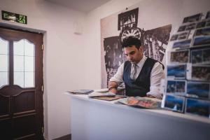 a man sitting at a counter looking at a newspaper at Villa Clock Tower - Саат Кула in Ohrid