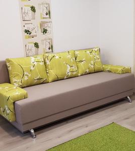 um sofá com almofadas amarelas num quarto em Green Apartman em Târgu-Mureş
