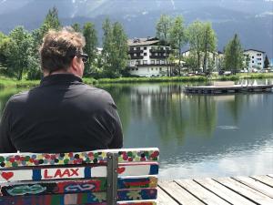 a man sitting on a bench looking at a lake at Ferienwohnung Laax mit Traumblick, großem Balkon und Terrasse in Laax