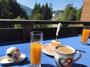 a table with a cup of orange juice and a plate of food at Ferienwohnung Laax mit Traumblick, großem Balkon und Terrasse in Laax