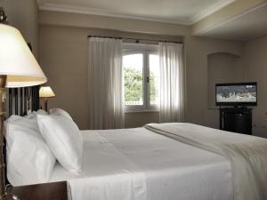 a bedroom with a white bed and a window at Solar De La Plaza in Salta