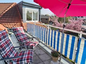 2 Stühle und ein Sonnenschirm auf dem Balkon in der Unterkunft Tova Cologne in Großkönigsdorf