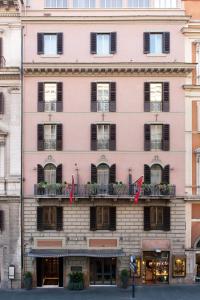 ローマにあるホテル マスカーニのピンクの建物(黒い窓とバルコニー付)
