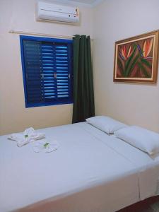 a bedroom with a white bed with a blue window at Hotel Ypê in Rio Verde