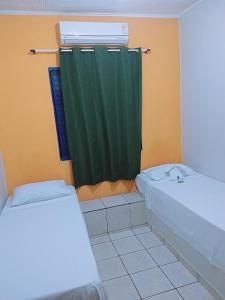 La salle de bains est pourvue d'un rideau de douche vert et de toilettes. dans l'établissement Hotel Ypê, à Rio Verde