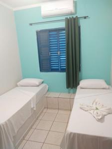 a blue room with two beds and a window at Hotel Ypê in Rio Verde