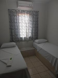 a small room with two beds and a window at Hotel Ypê in Rio Verde