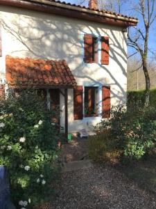 a white house with brown windows and bushes at Maison L’allee in Lézignac-Durand