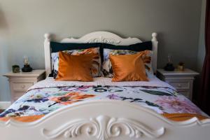 een groot wit bed met kleurrijke kussens erop bij B&B Wilhelmina's Cottage in Ridderkerk