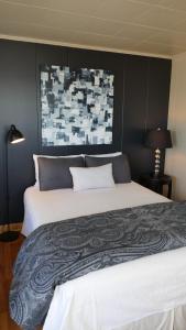 a bedroom with a large bed with a black wall at Hôtel-Motel Vagues Vertes in Perce