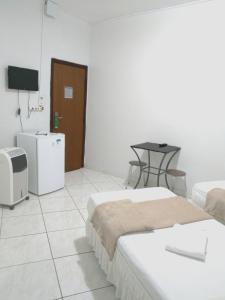 a room with two beds and a tv and a table at Hotel Araguaia Goiânia in Goiânia