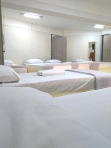 Hotel Araguaia Goiânia في غويانيا: غرفة بها مجموعة من الأسرة البيضاء
