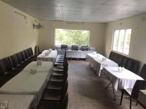 a room with rows of tables and chairs with white tables at Pine Park Lodges in Shāhkot