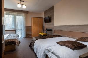 a hotel room with two beds and a flat screen tv at Penzion Limba in Liptovský Ján
