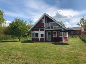 ein kleines rotes Haus mit einem Rasenplatz in der Unterkunft Norweger Haus am Tollensesee in Groß Nemerow