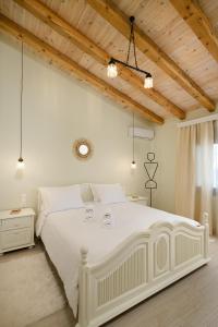 Habitación blanca con cama blanca grande y techo de madera. en Aphrodite Mountain View en Périon