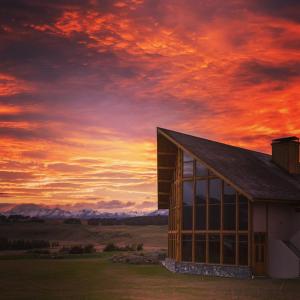 a building with a sunset in the background at Fiordland Lodge in Te Anau