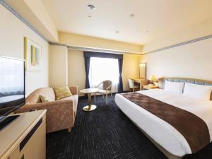 um quarto de hotel com uma cama grande e um sofá em Hotel Sapporo Garden Palace em Sapporo