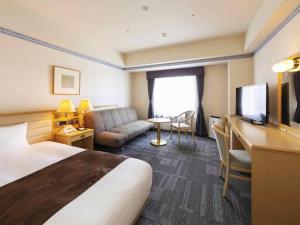 a hotel room with a bed and a couch and a television at Hotel Sapporo Garden Palace in Sapporo