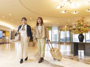 two women walking in a lobby with a suitcase at Hotel Sapporo Garden Palace in Sapporo