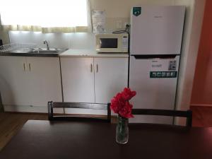 un jarrón de flores rojas sentado en una mesa en una cocina en Oakridge Motel Tourist Park en Oakey