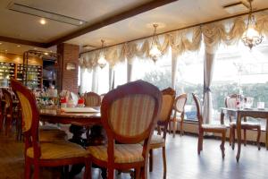 a dining room with a table and chairs and windows at Hotel Noborisaka in Fujikawaguchiko