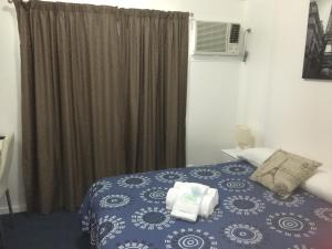 Oakridge Motel Tourist Park في Oakey: غرفة نوم بسرير ازرق ونافذة