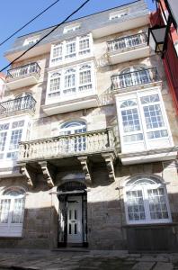 un edificio con finestre bianche e balcone di Hotel Larry a Cee