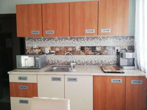 cocina con armarios de madera, fregadero y microondas en Guest House Plavas, en Sozopol